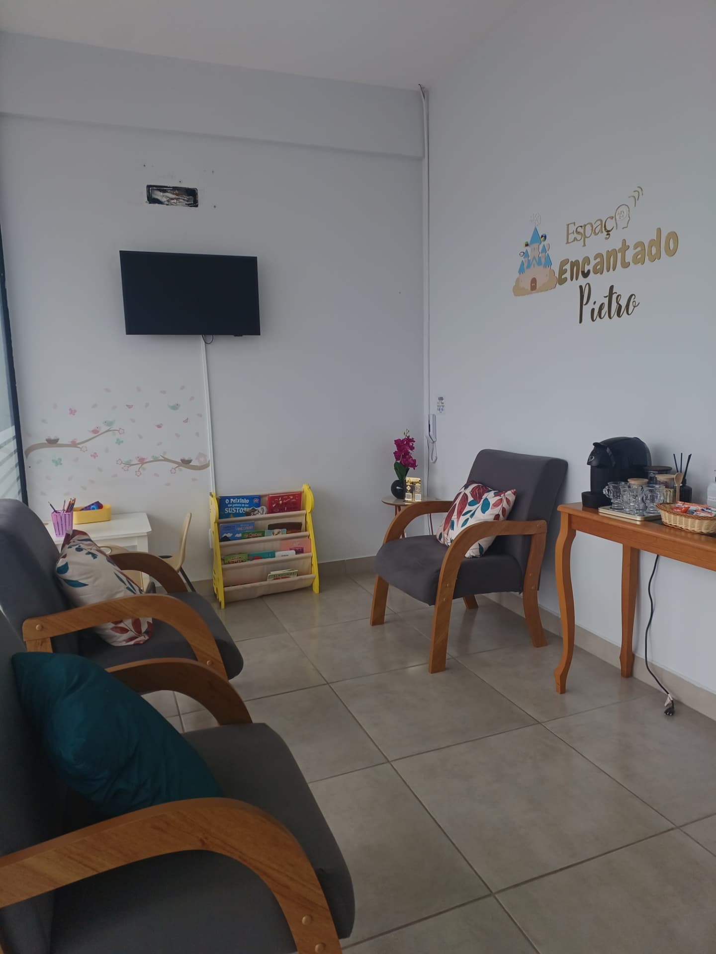 Recepção do Espaço Encantado Pietro com poltronas, livros infantis e mesa de acolhimento